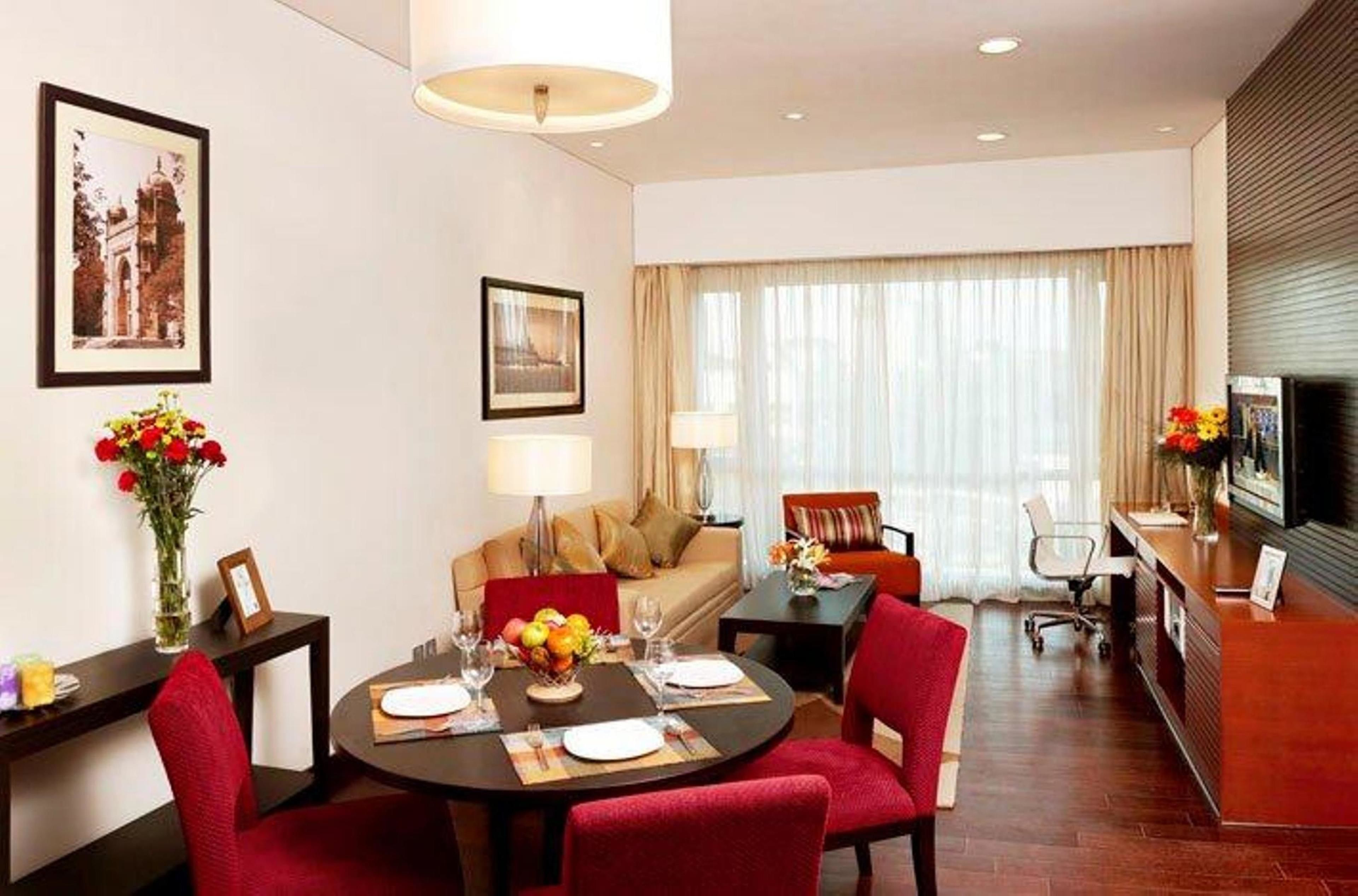 Habitación de hotel con comedor, sofá, televisor y escritorio.