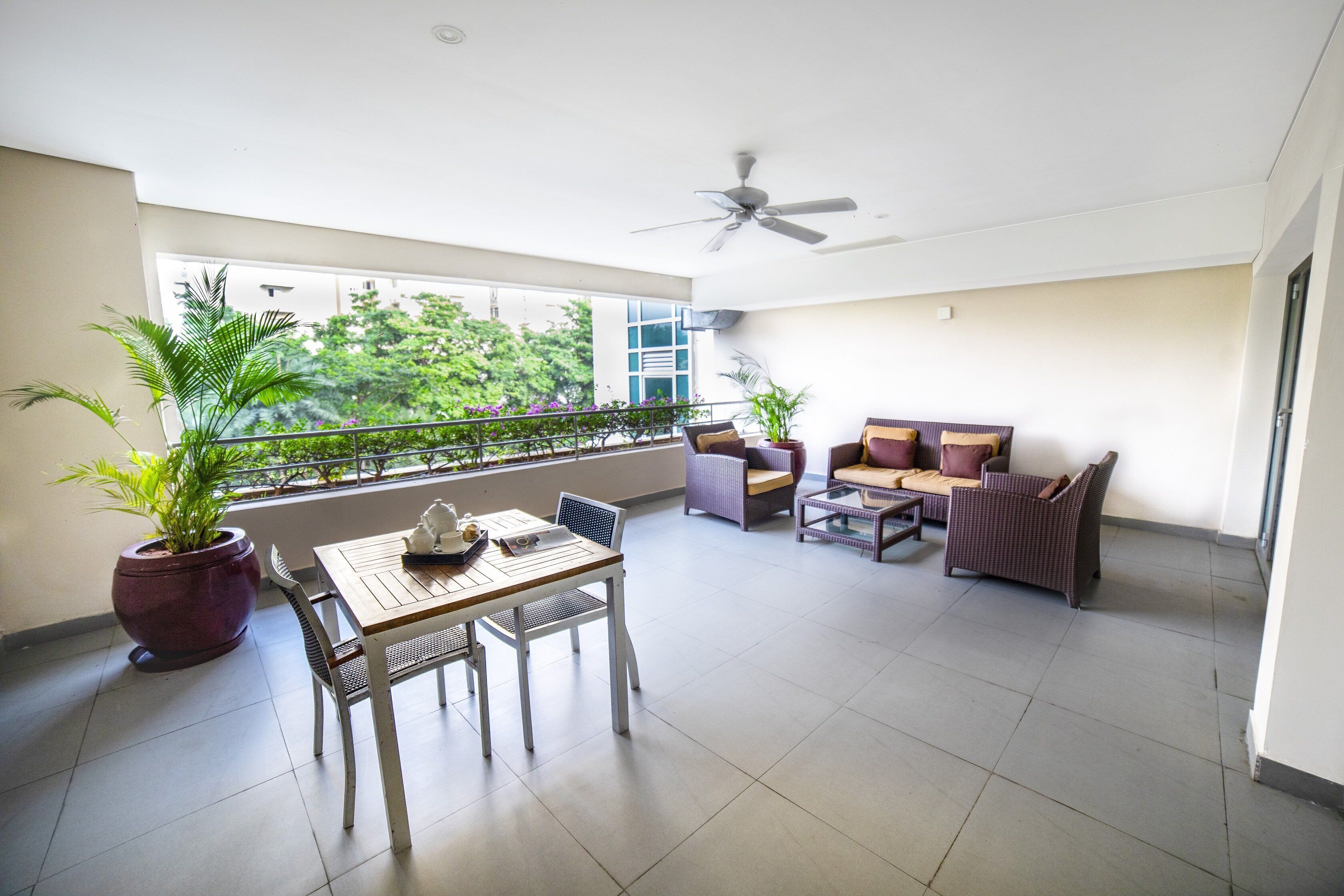 A spacious balcony with a dining area, seating, and potted plants.