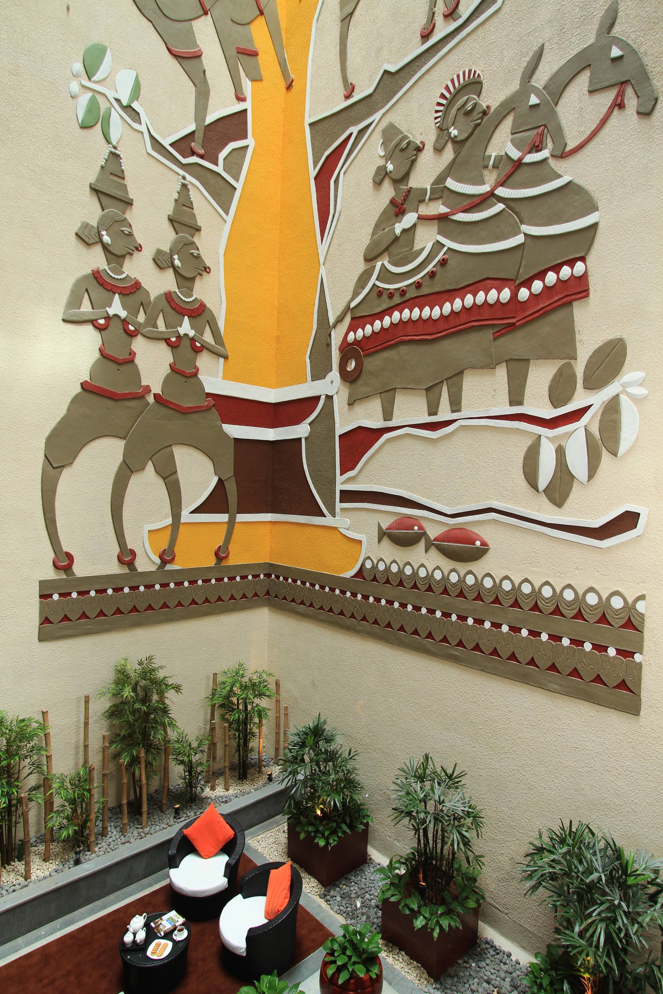 A wall mural with a tree and figures, a seating area with cushions, and potted plants.