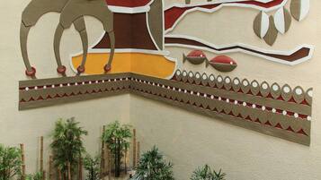 A wall mural with a tree and figures, a seating area with cushions, and potted plants.