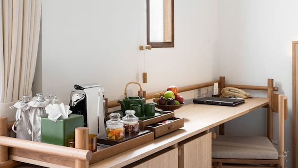 A kitchenette with a wooden countertop, a kettle, a bowl of fruit, and a laptop. - SALA Samui Choengmon Beach (Koh Samui)