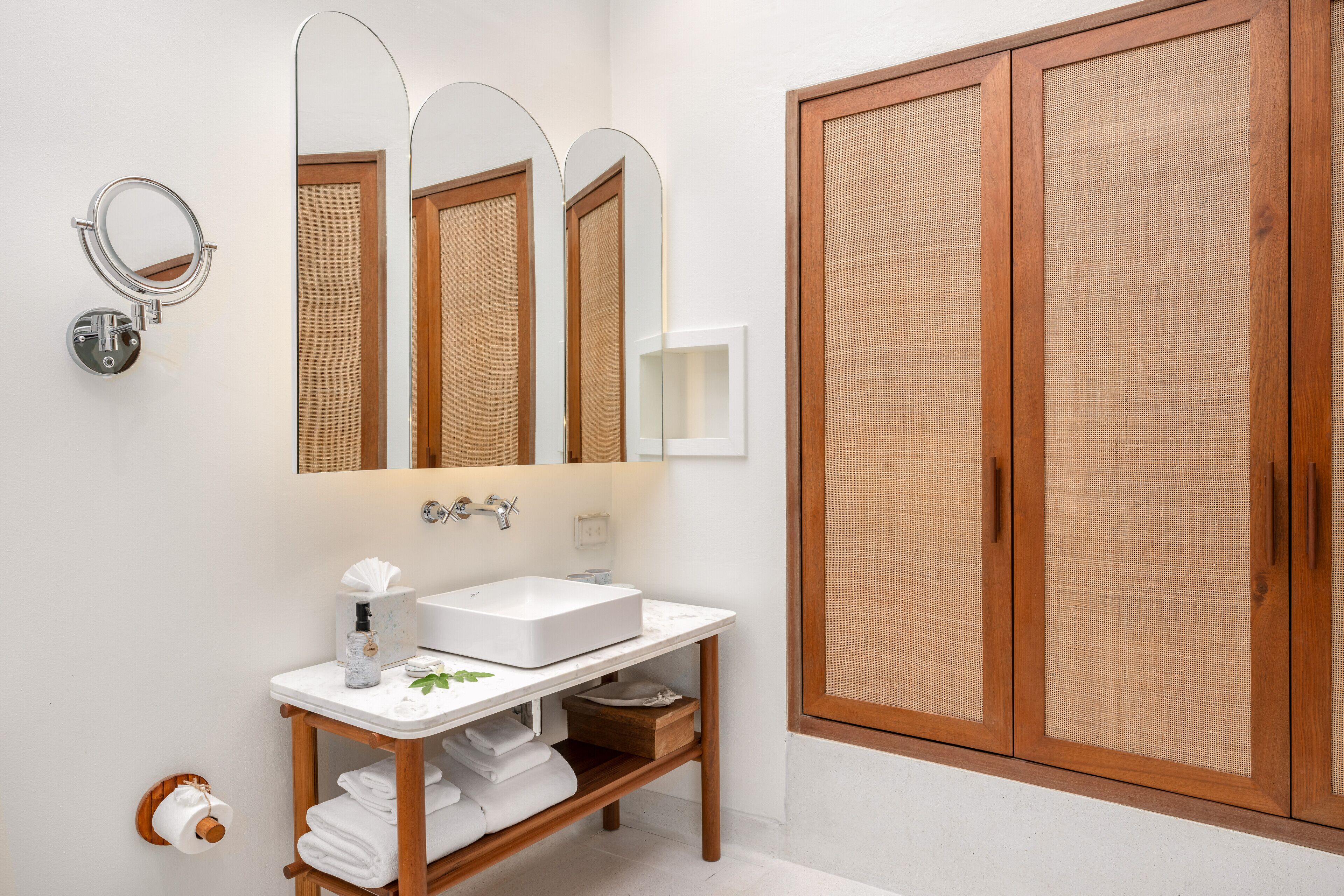 A bathroom with a white sink, a mirror, and wooden cabinets.