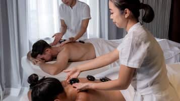 A massage therapy session in a room with a bed and a massage table.