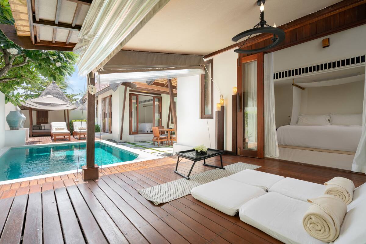 A wooden deck with a pool, a sofa, and a table.