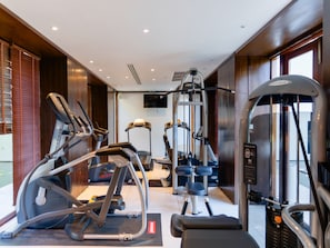 Un gimnasio con diversos equipos de ejercicio, incluyendo cintas de correr, elípticas y máquinas de pesas.