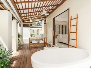 Casa de banho moderna com banheira independente, soalho em madeira e ventoinha no teto.