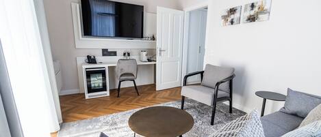 Una sala moderna con sofá, una mesa de centro y un televisor sobre una zona de cocina.