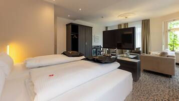A hotel room with two beds, a TV, a desk, a sofa, and a wardrobe.