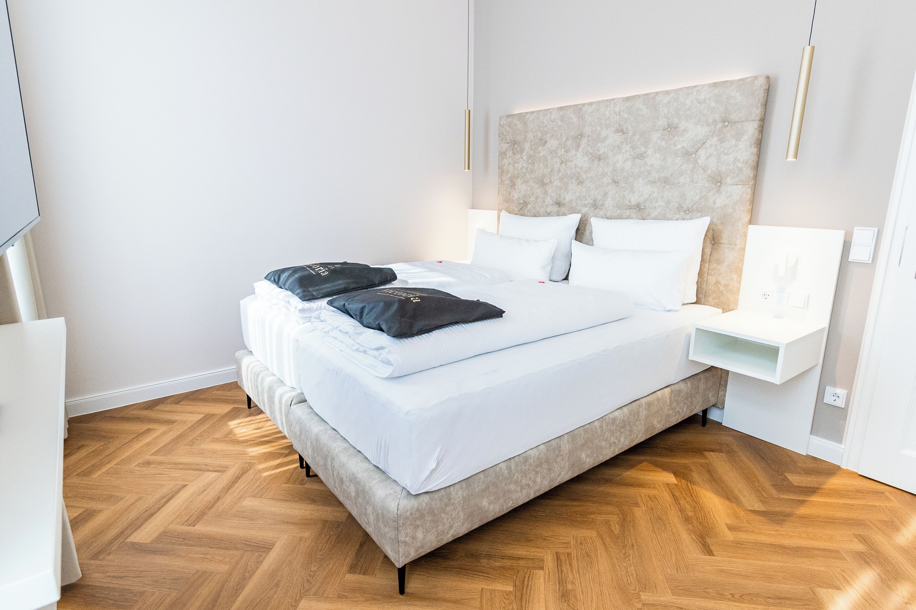 A modern hotel room with a large bed, a bedside table, and a TV.
