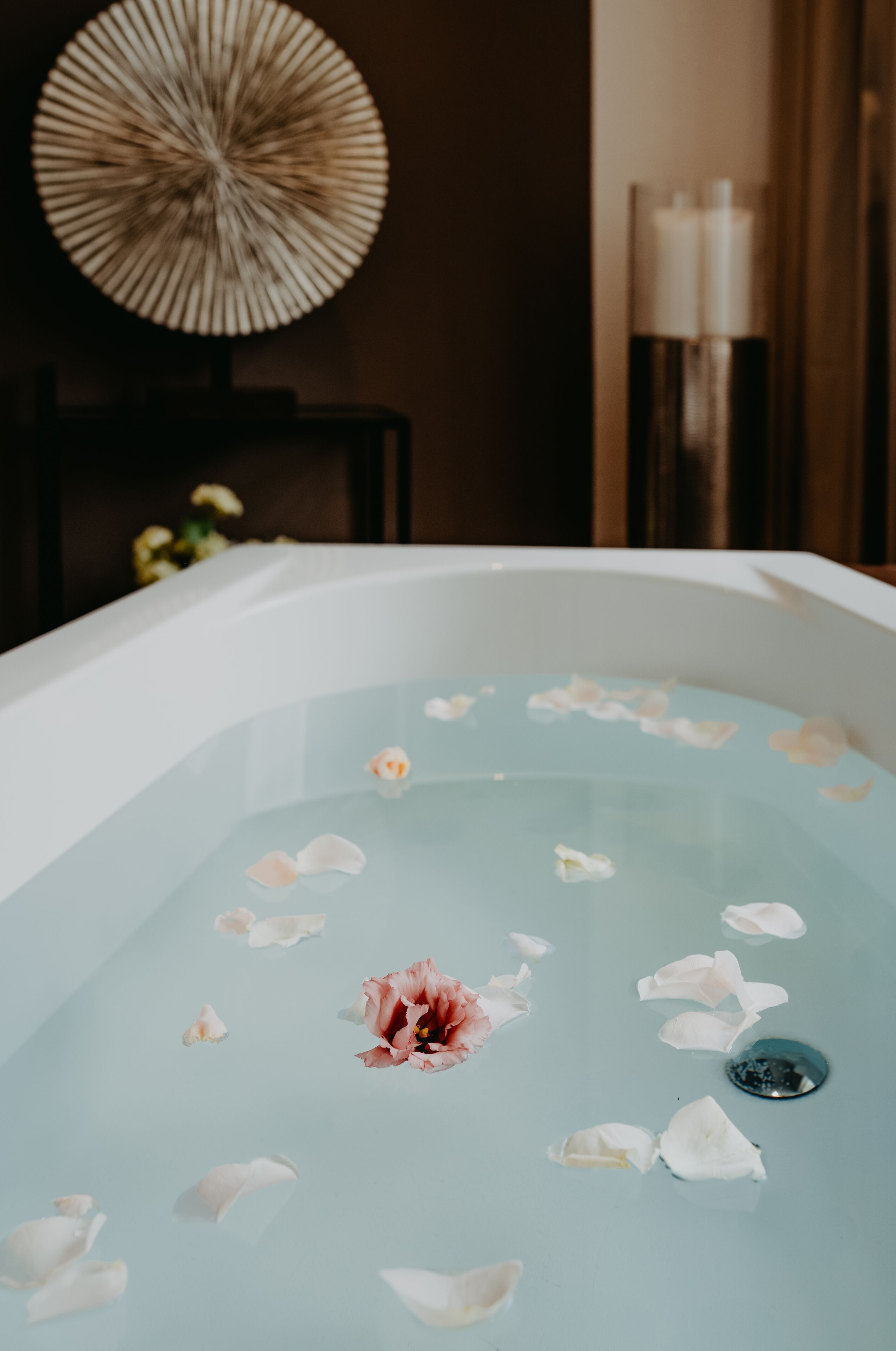 A bathtub filled with water and rose petals.