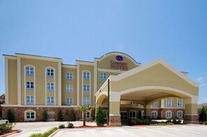 Welcome to Comfort Suites, featuring a modern architectural design with a central entrance and landscaped outdoor space.