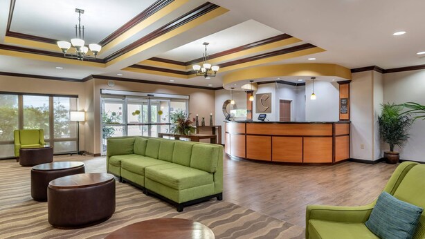 A lobby with a reception desk, green sofas, and a patterned carpet. - Comfort Suites Vicksburg (Vicksburg)