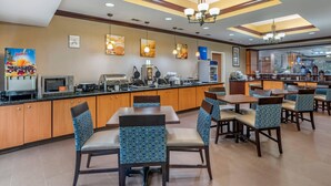A modern hotel dining area with a counter, seating, and a view of the kitchen. - Comfort Suites Vicksburg (Vicksburg)