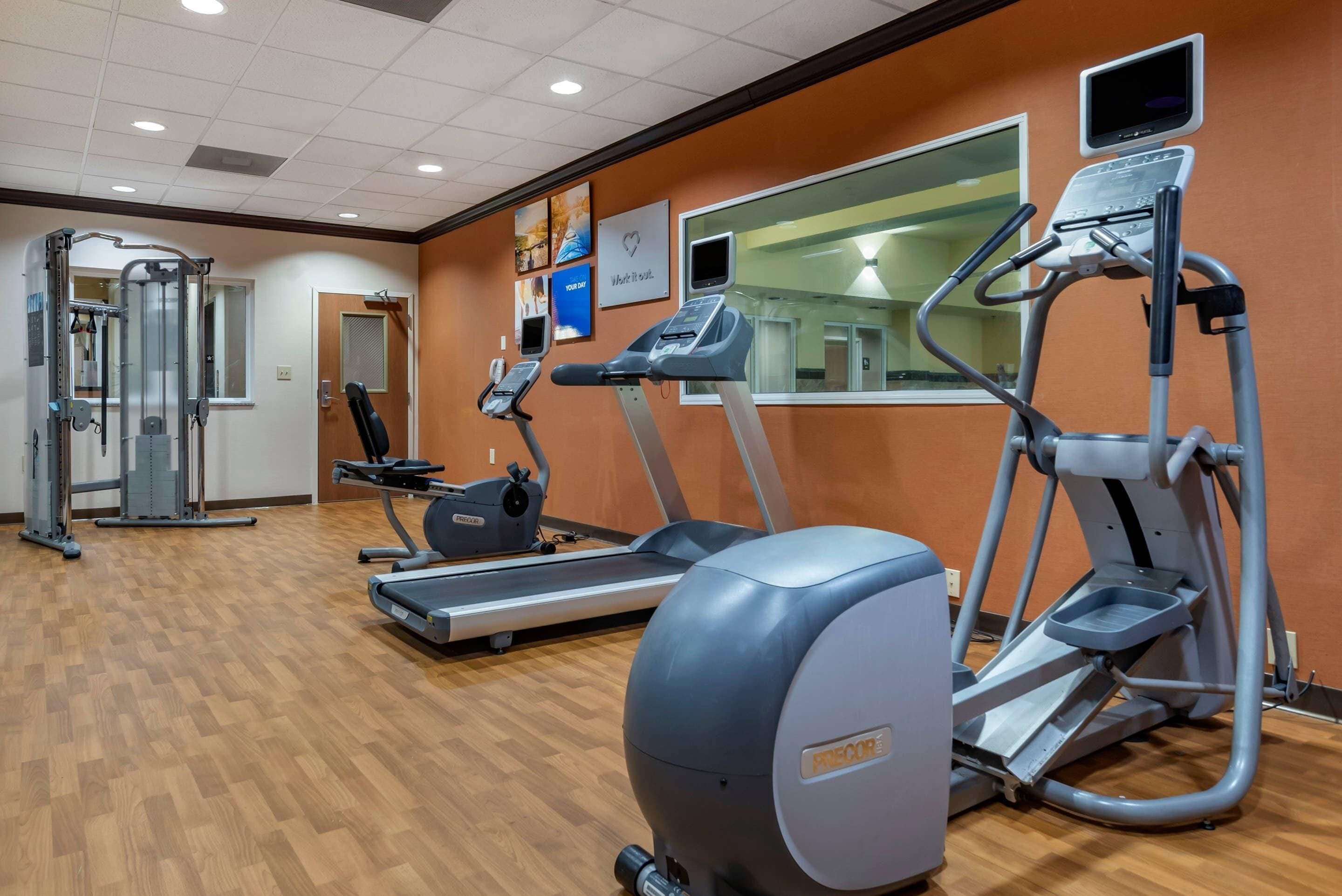 A gym with treadmills, elliptical machines, and a weight machine.