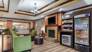 A hotel lobby with a fireplace, seating area, and a beverage refrigerator. - Comfort Suites Vicksburg (Vicksburg)
