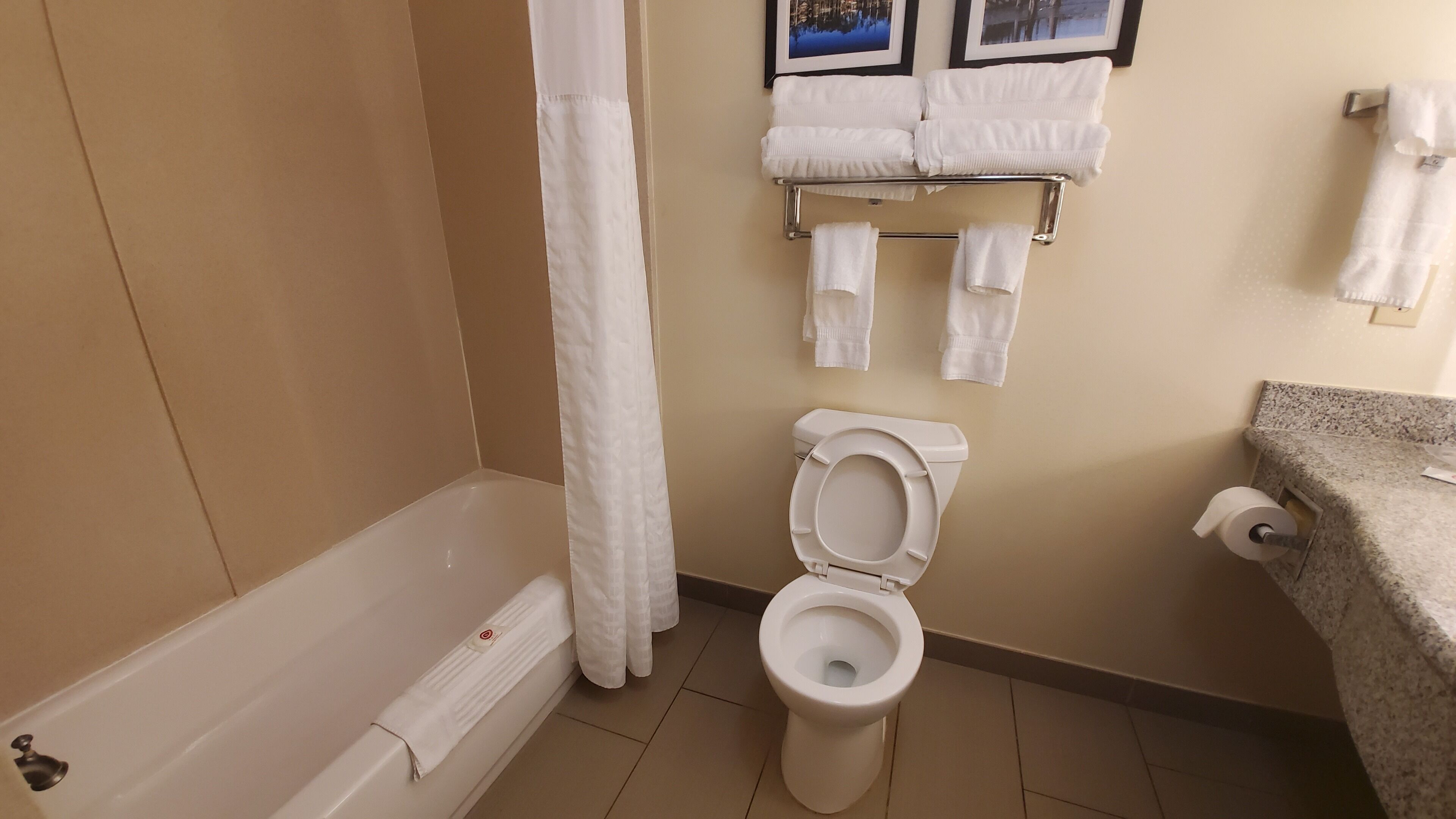 Un baño con bañera, inodoro y un perchero con toallas.