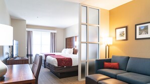 A hotel room with a bed, a sofa, a desk, and a TV. - Comfort Suites Vicksburg (Vicksburg)