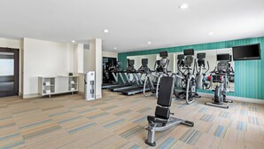 Un gimnasio con cintas de correr, elípticas y una banca de pesas.