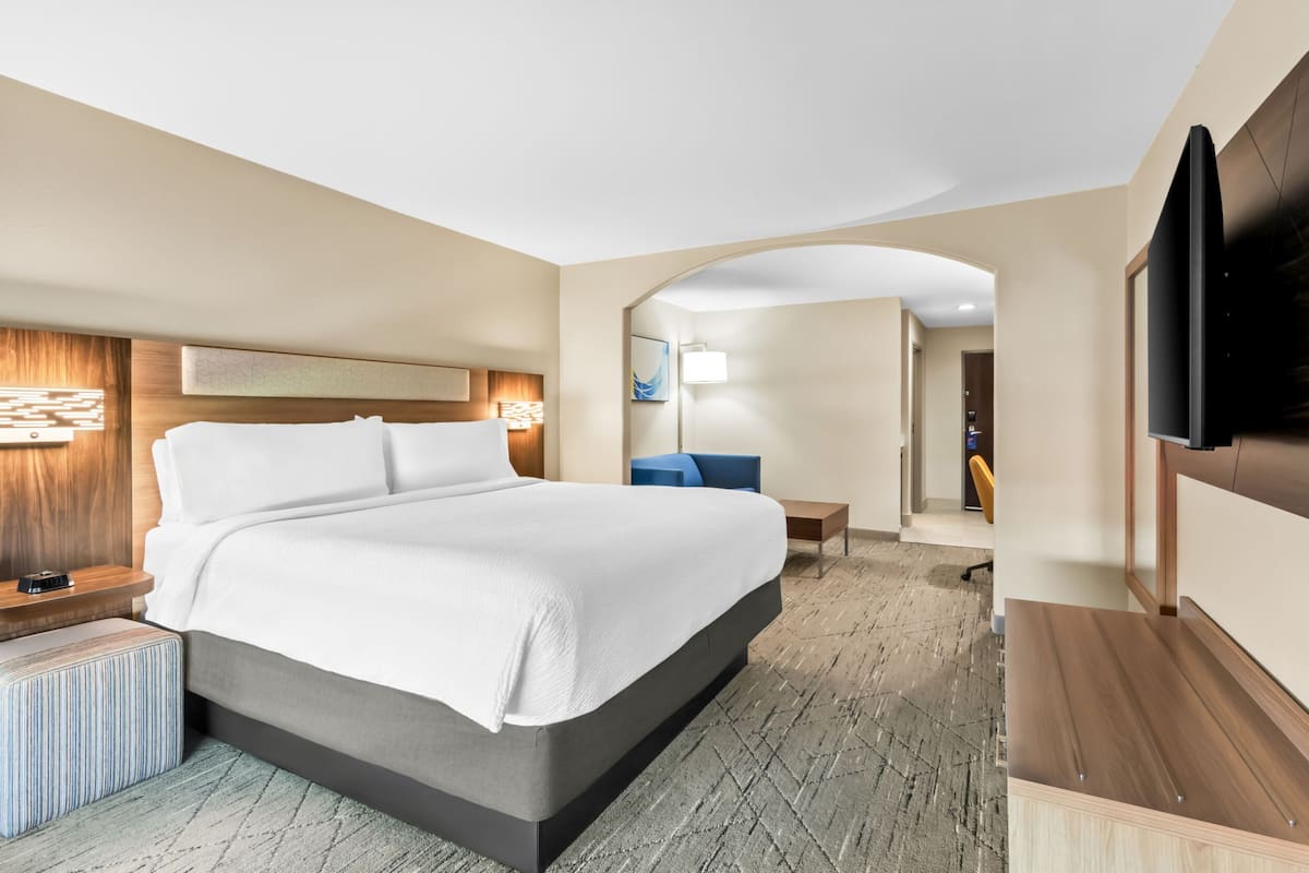 A modern hotel room with a large bed, a desk, and a TV.