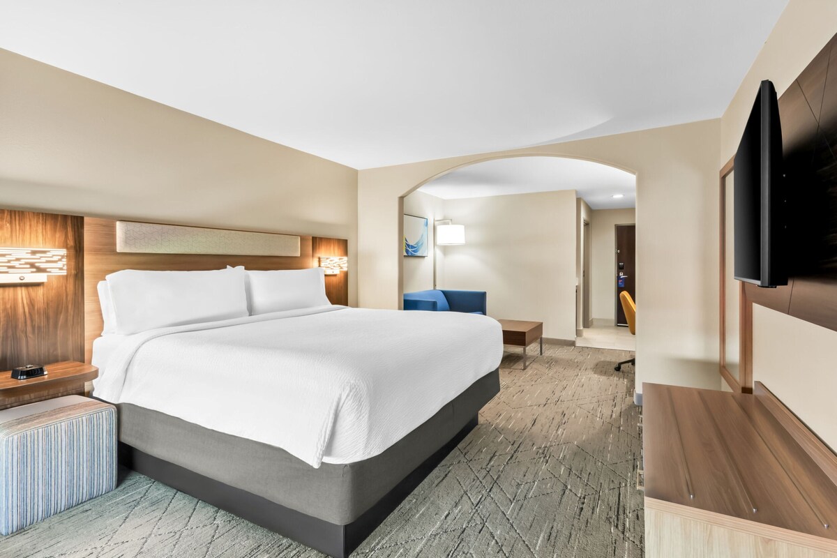 A modern hotel room with a large bed, a desk, and a TV.