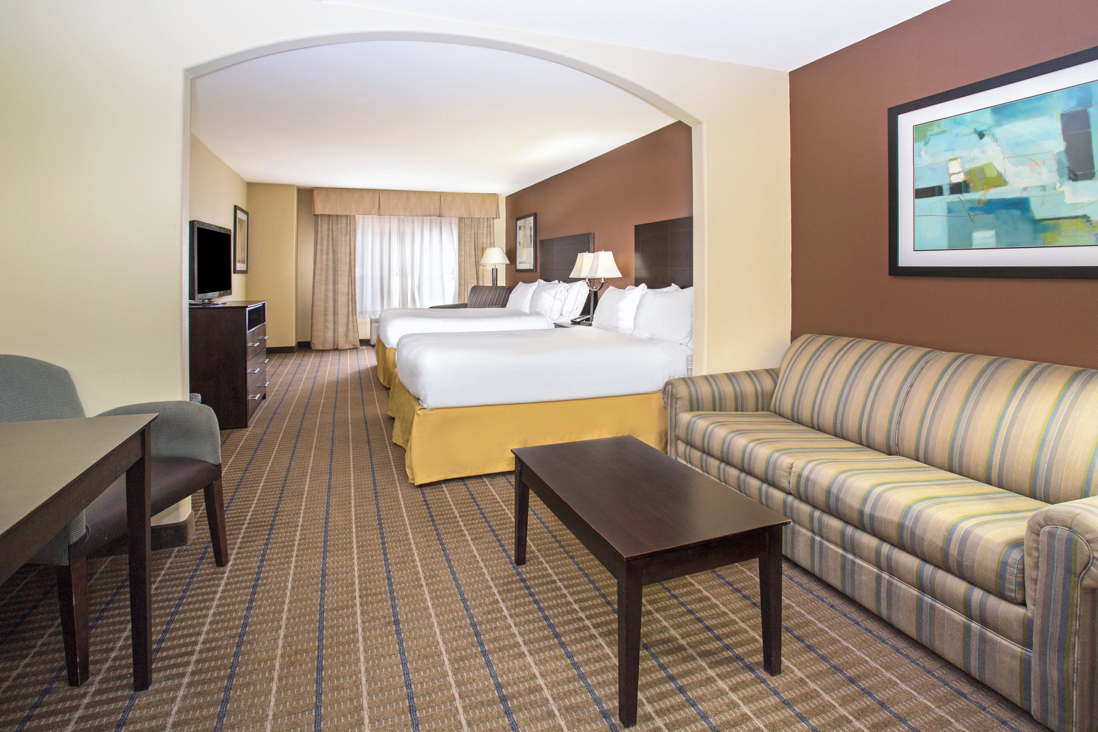 Una habitación de hotel con una cama, un sofá, un escritorio y una televisión.