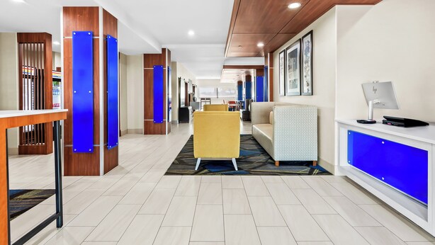 Un hall de hotel con un mostrador de recepción, un sillón amarillo, un sofá y una alfombra estampada.