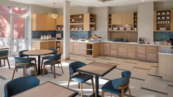 Eine moderne Küche mit Holzausstattung, einer zentralen Kochinsel und einem Essbereich mit blauen Stühlen und einem runden Tisch.