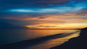Una playa con un atardecer sobre el agua.