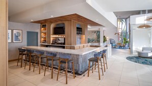 A modern kitchen with a central island, bar stools, and a built-in TV.