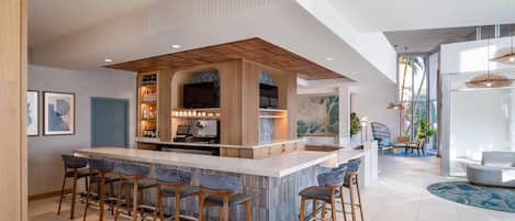 A modern kitchen with a bar area, bar stools, and a large window.