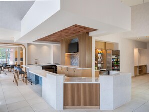 Una cocina moderna con una isla central, electrodomésticos integrados y una zona de comedor con taburetes de bar.