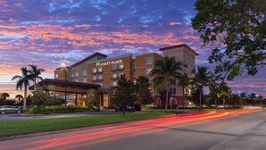 A multi-story hotel with a prominent "Hyatt Place" sign, surrounded by palm trees and a well-maintained lawn.