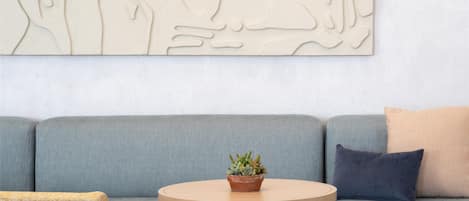 A modern living room with a grey sofa, a round wooden coffee table, and a woven chair.