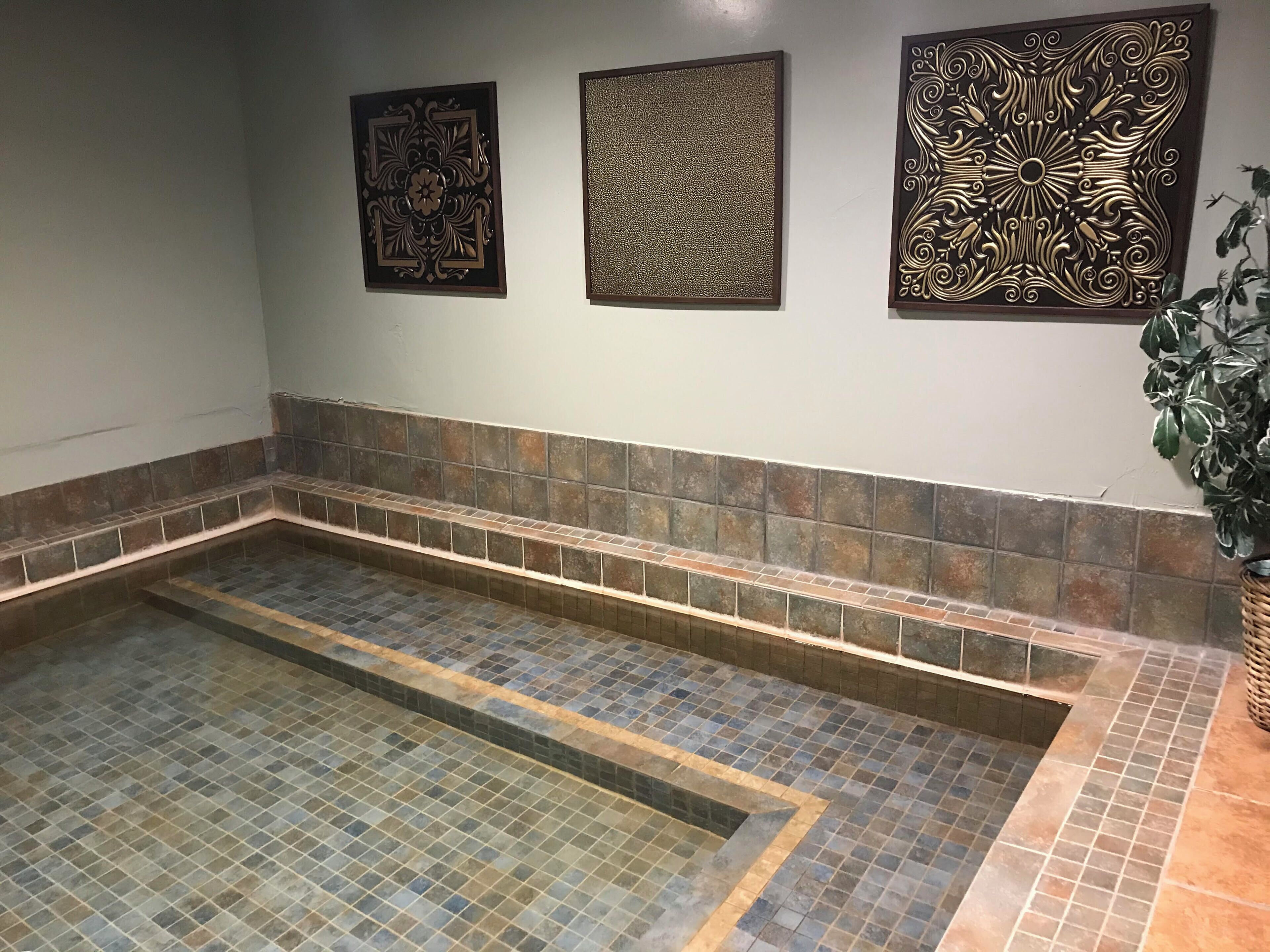 A spa area with a tiled floor, a bench, and decorative wall panels.