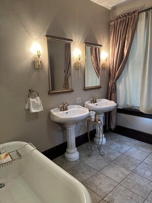 A bathroom with two sinks, a bathtub, and two wall-mounted mirrors.