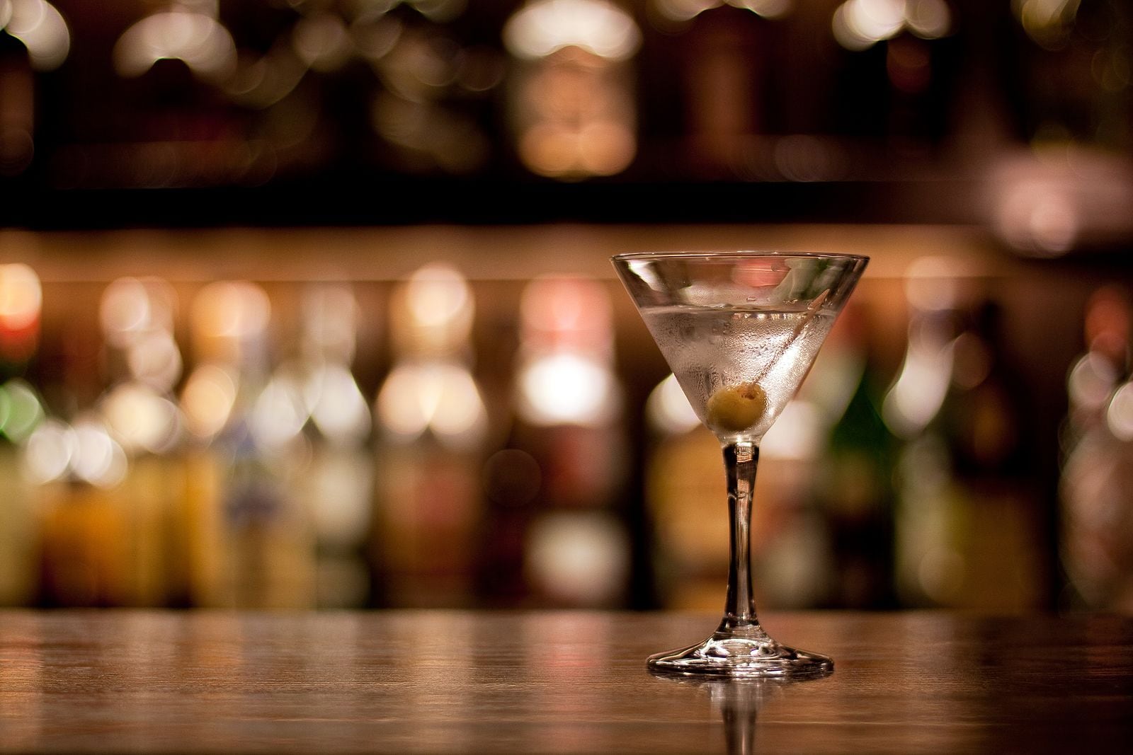 Een martini glas met een citroen twist op een barkruk.