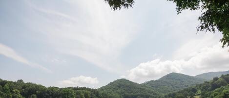 A golf course with rolling hills, trees, and a mountain in the background.
