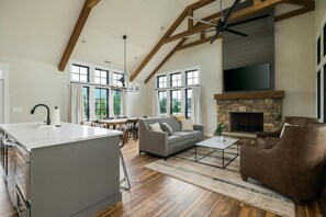 A spacious living area with a large island, a stone fireplace, and a dining area with natural light.