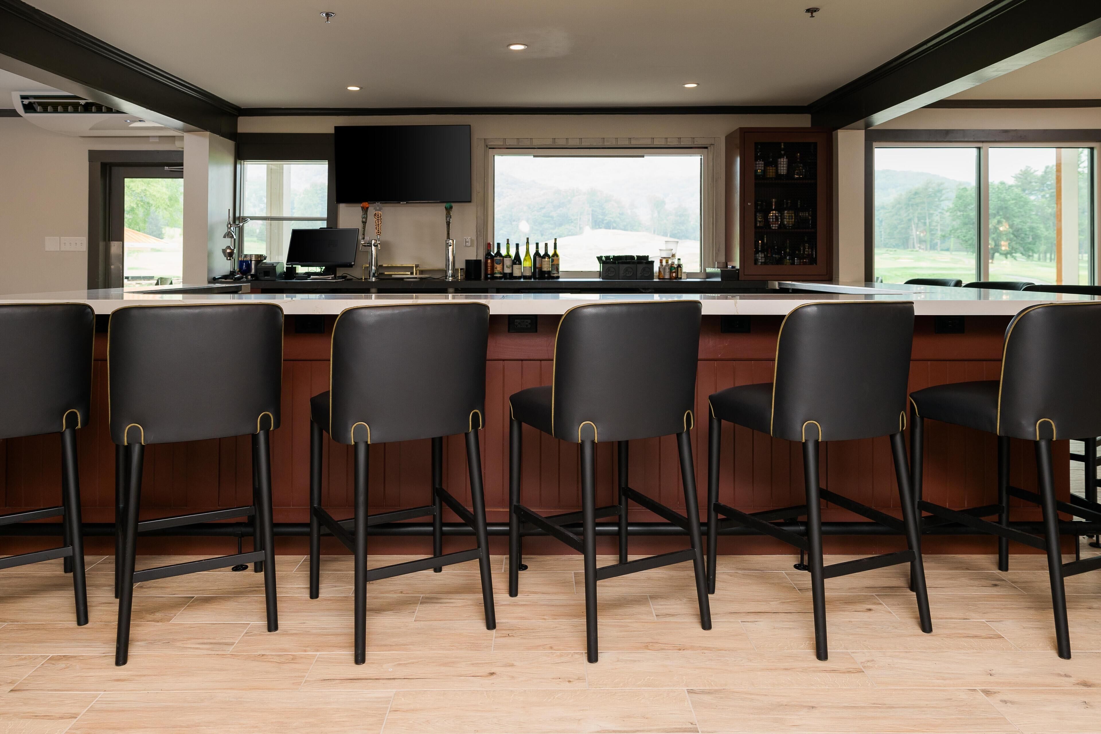 Une cuisine moderne dotée d’un grand îlot central, de tabourets de bar et d’un meuble à vin.