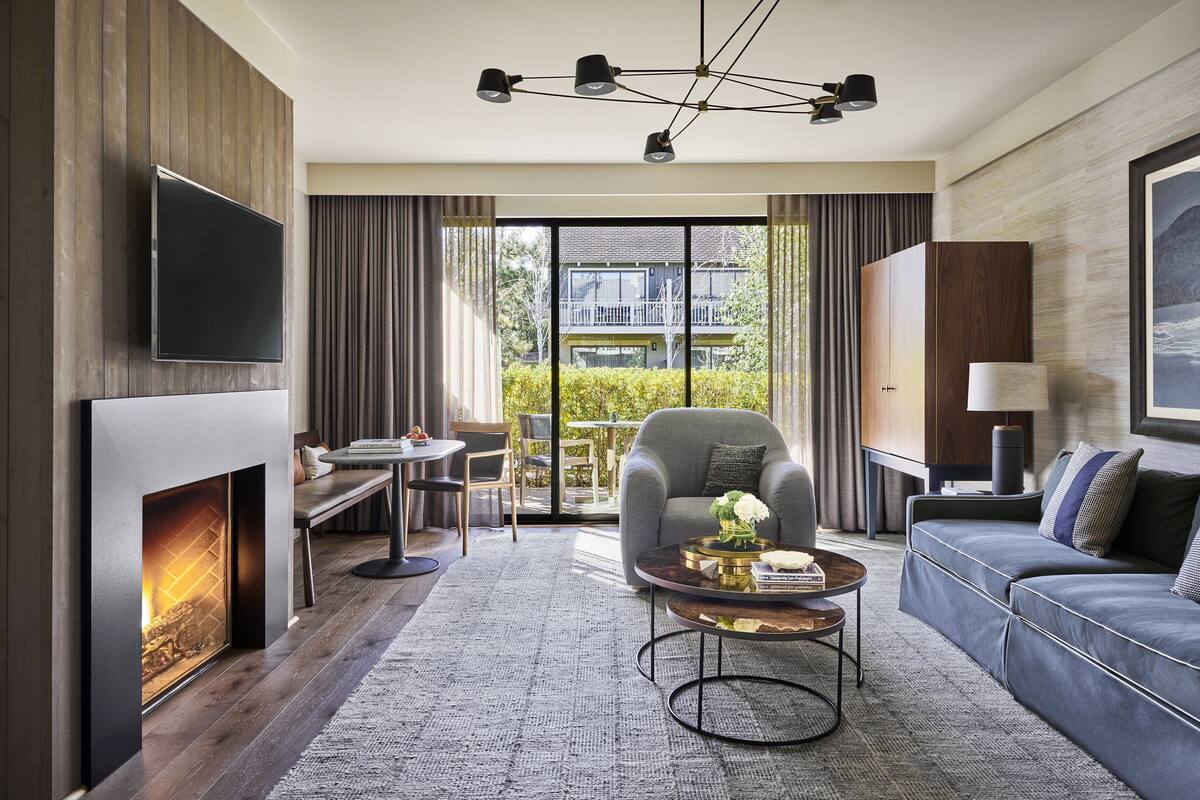 Una sala moderna con chimenea, televisor de pantalla plana, sofá, mesa de centro y comedor con mesa y sillas.