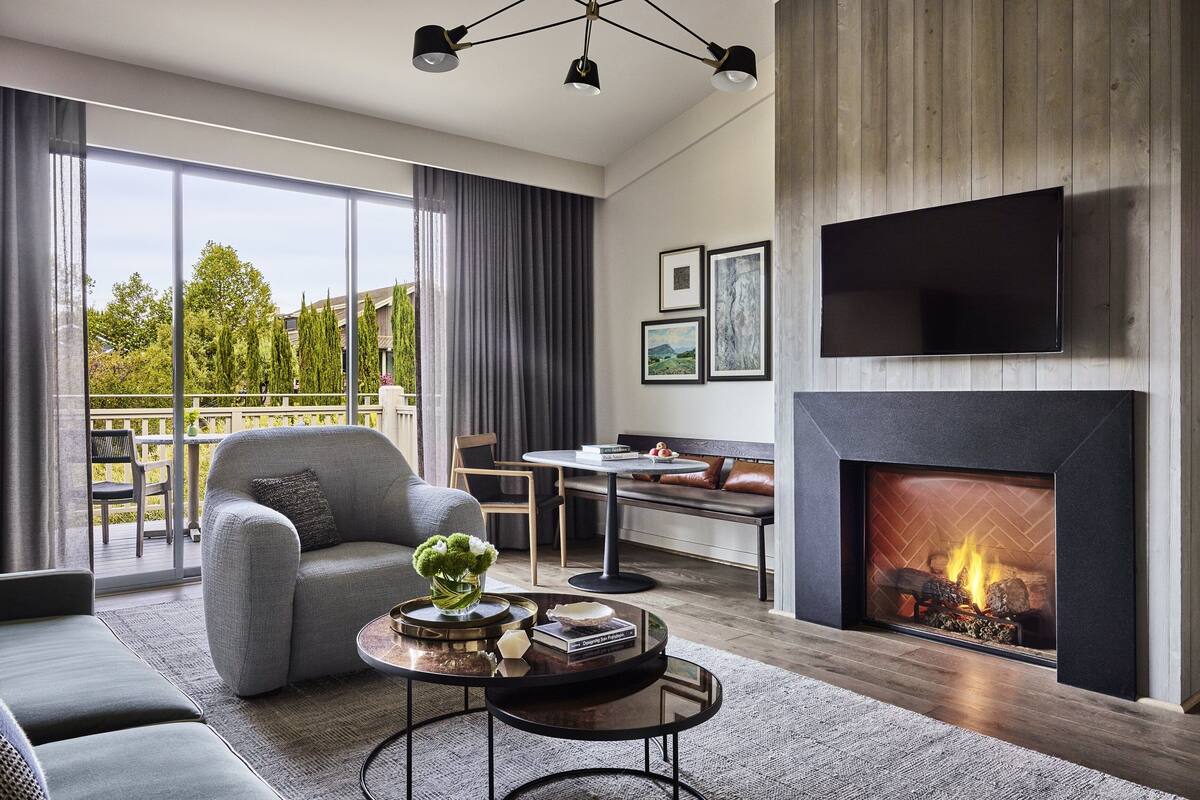 Una sala de estar moderna con chimenea, ventanas amplias y un balcón.