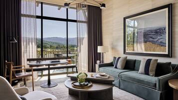 A modern living room with a sofa, coffee table, and a dining area with a table and chairs.