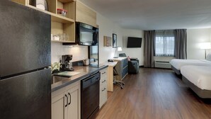 A compact hotel room with a kitchenette, a bed, a desk, and a TV. - Candlewood Suites Lexington by IHG (Lexington)