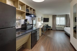A compact hotel room with a kitchenette, a bed, a desk, and a television. - Candlewood Suites Lexington by IHG (Lexington)