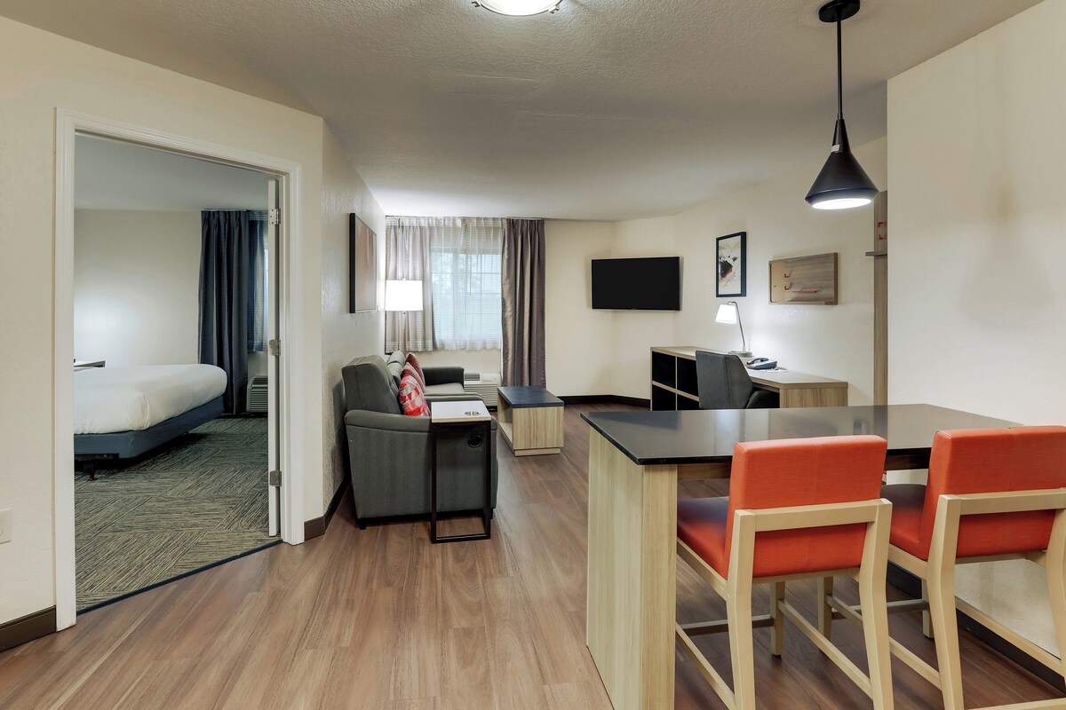 A hotel room with a bed, a desk, a chair, a TV, and a window with curtains.