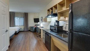 A compact hotel room with a kitchenette, a bed, a desk, and a TV. - Candlewood Suites Lexington by IHG (Lexington)