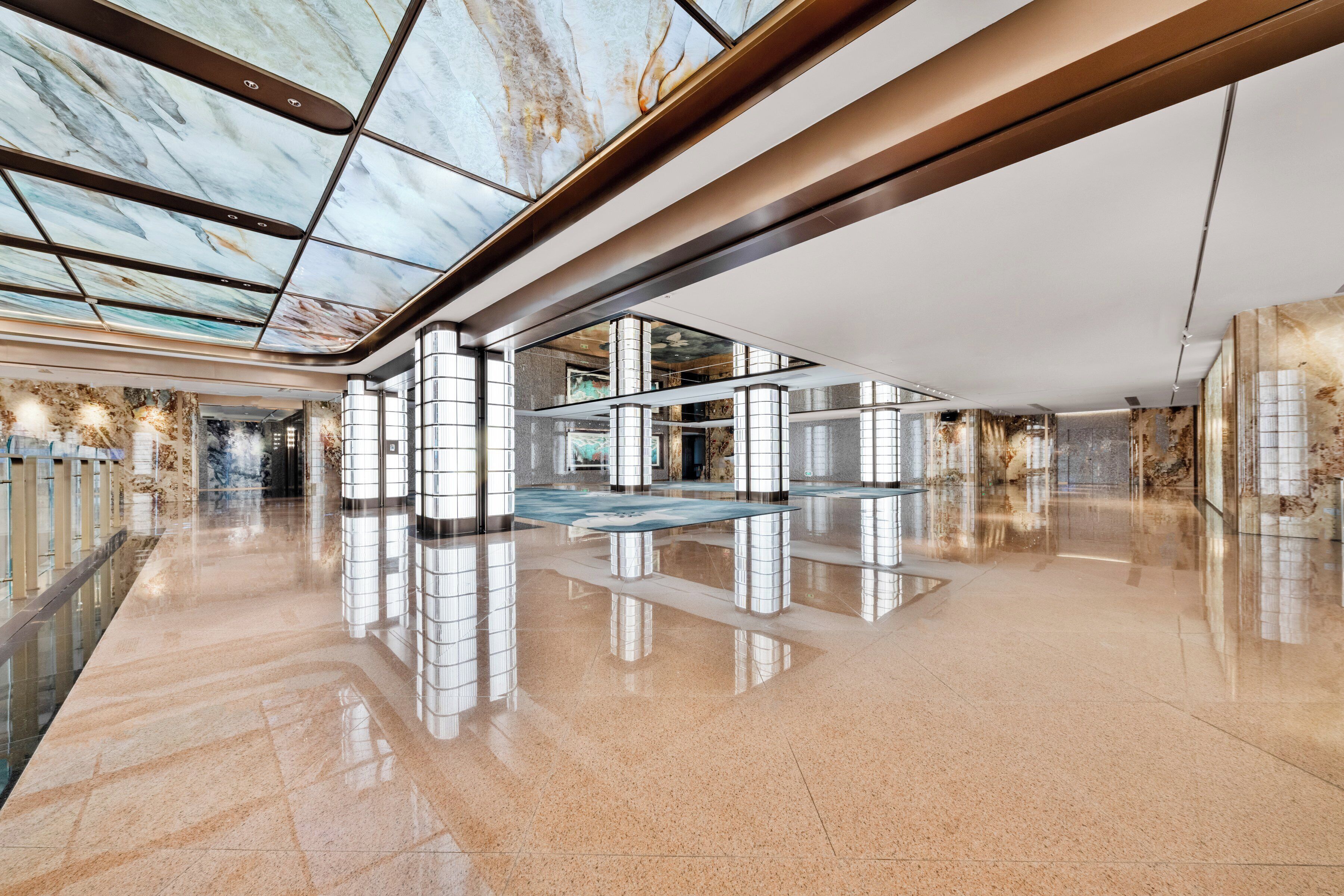 A spacious lobby with a high ceiling, reflective floor, and a central seating area.