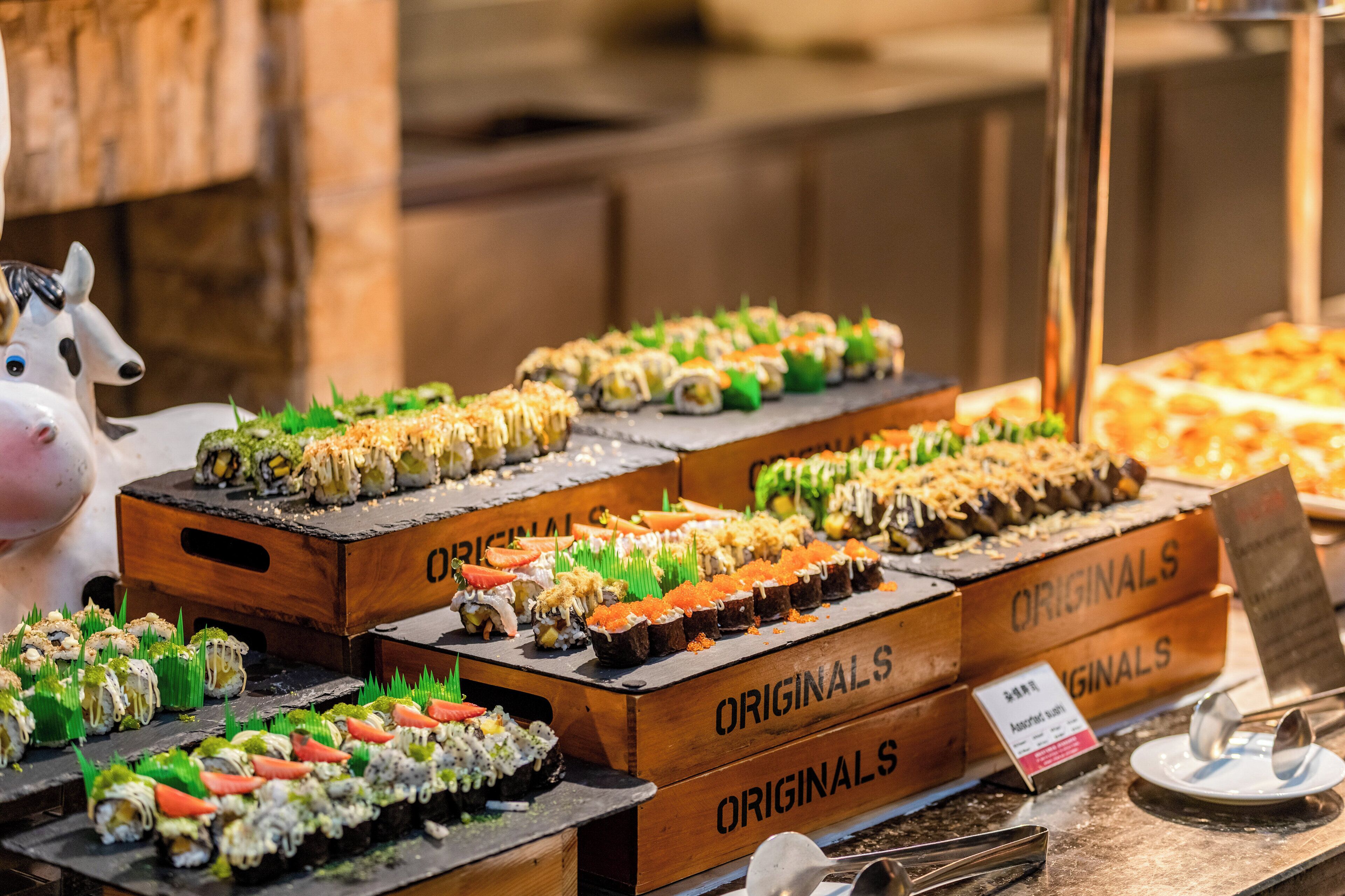 Presentación de sushi con diversos tipos de sushi sobre bandejas de madera que dicen 'ORIGINALS'.