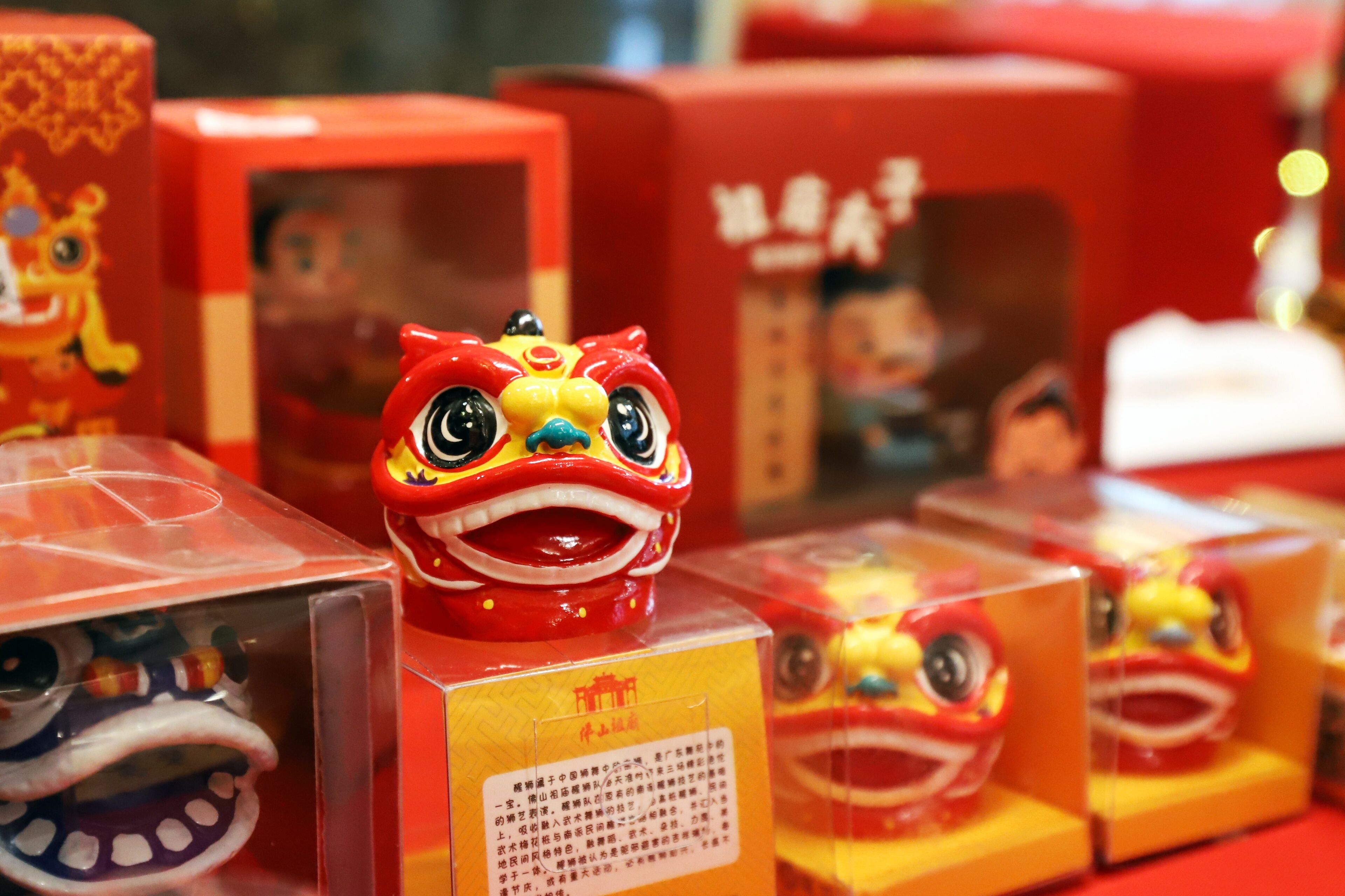 A display of red and yellow lion dance figures in boxes.