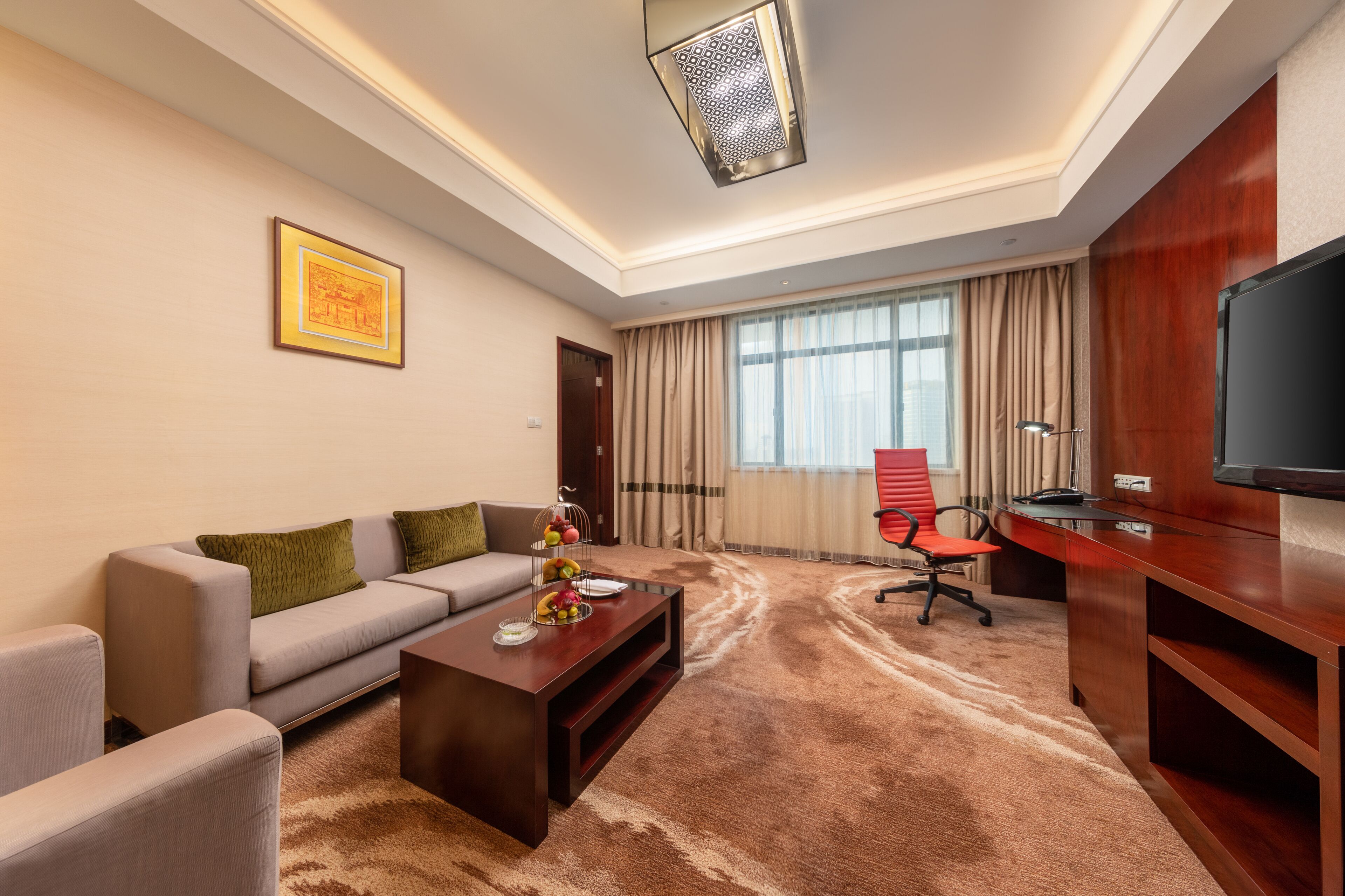 A modern living room with a sofa, coffee table, TV, and a red office chair.